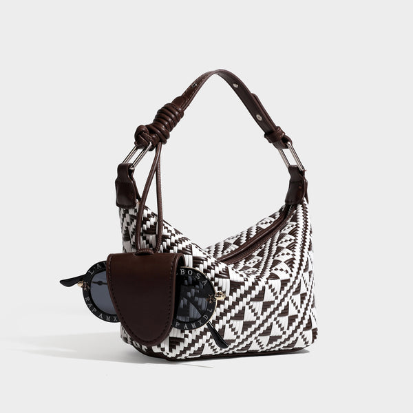 Kleine gewebte Schultertasche mit geometrischem Schwarz-Weiß-Muster, glatten dunkelbraunen Details in Lederoptik, geknotetem verstellbarem Riemen, Seitenansicht