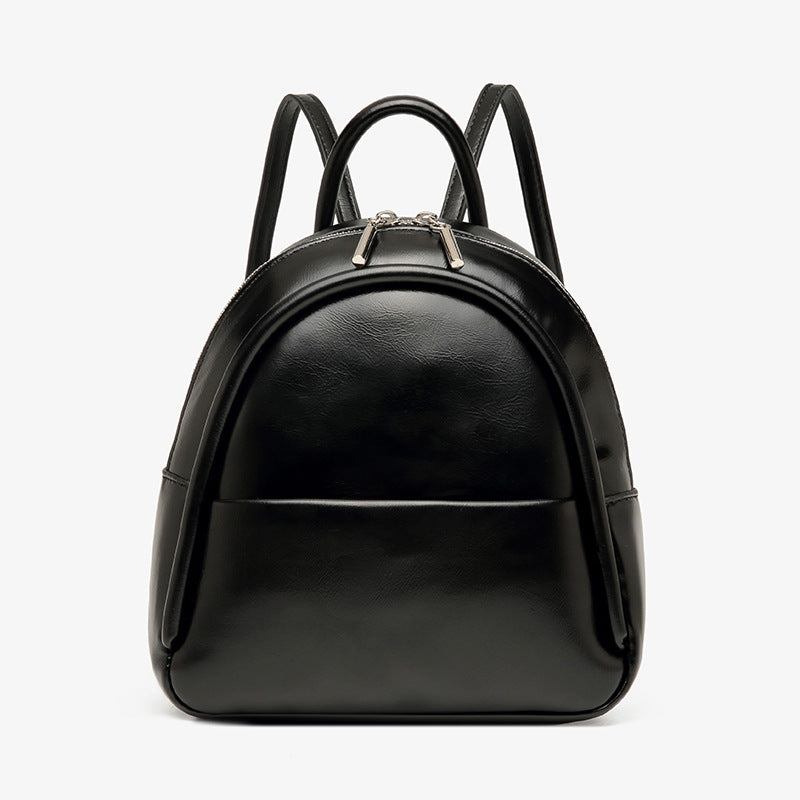 Kleine kuppelförmige Mini-Rucksackhandtasche in Pastellgelb mit glatter Oberfläche in Lederoptik, bogenförmigem Reißverschluss oben und silberfarbenen Details
