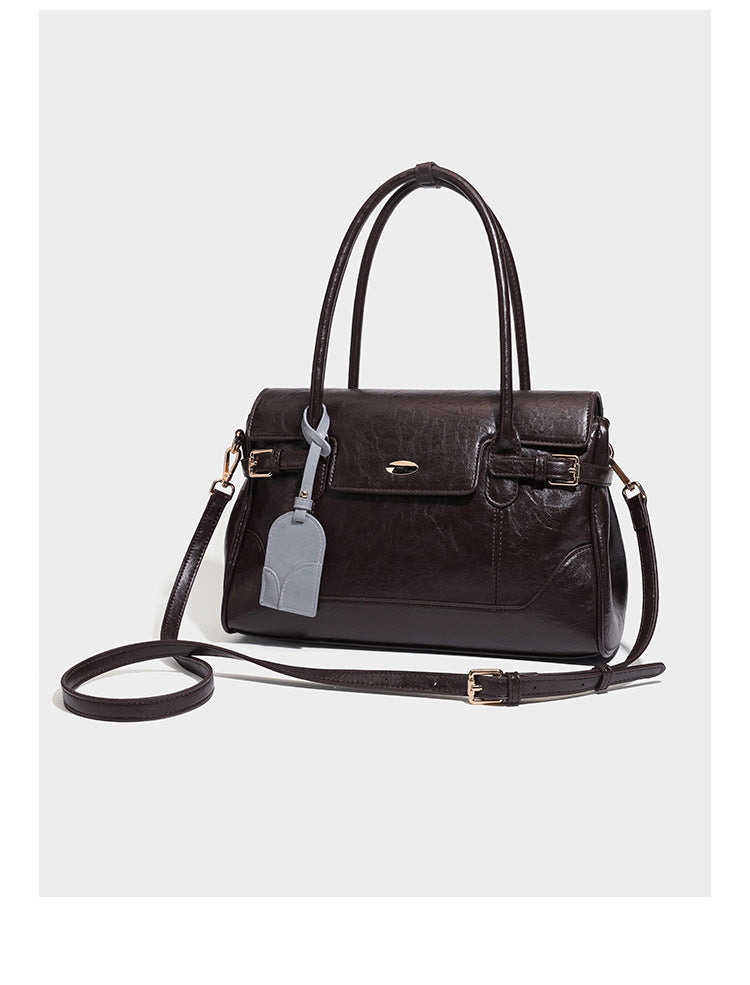 Structured glossy leather-look satchel bag with flap closure, gold-tone buckle accents, double top handles, detachable