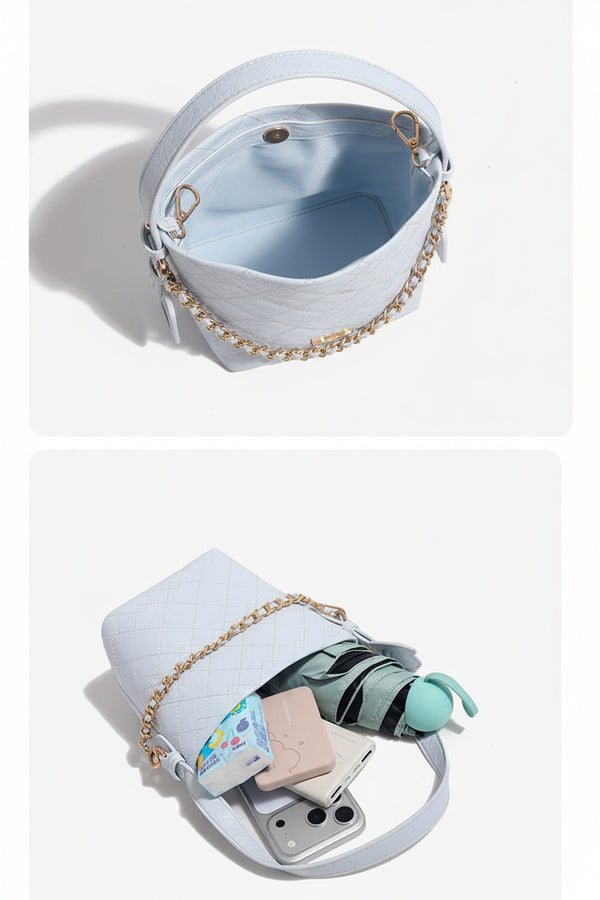 Small diamond-quilted bucket bag with gold-tone chain accent, heart strap detail, hanging tag, and matching zip coin pouch