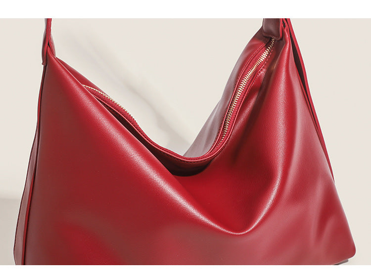 Large slouchy hobo shoulder bag in smooth leather-look finish with single long strap and gold-tone zip closure, detail view