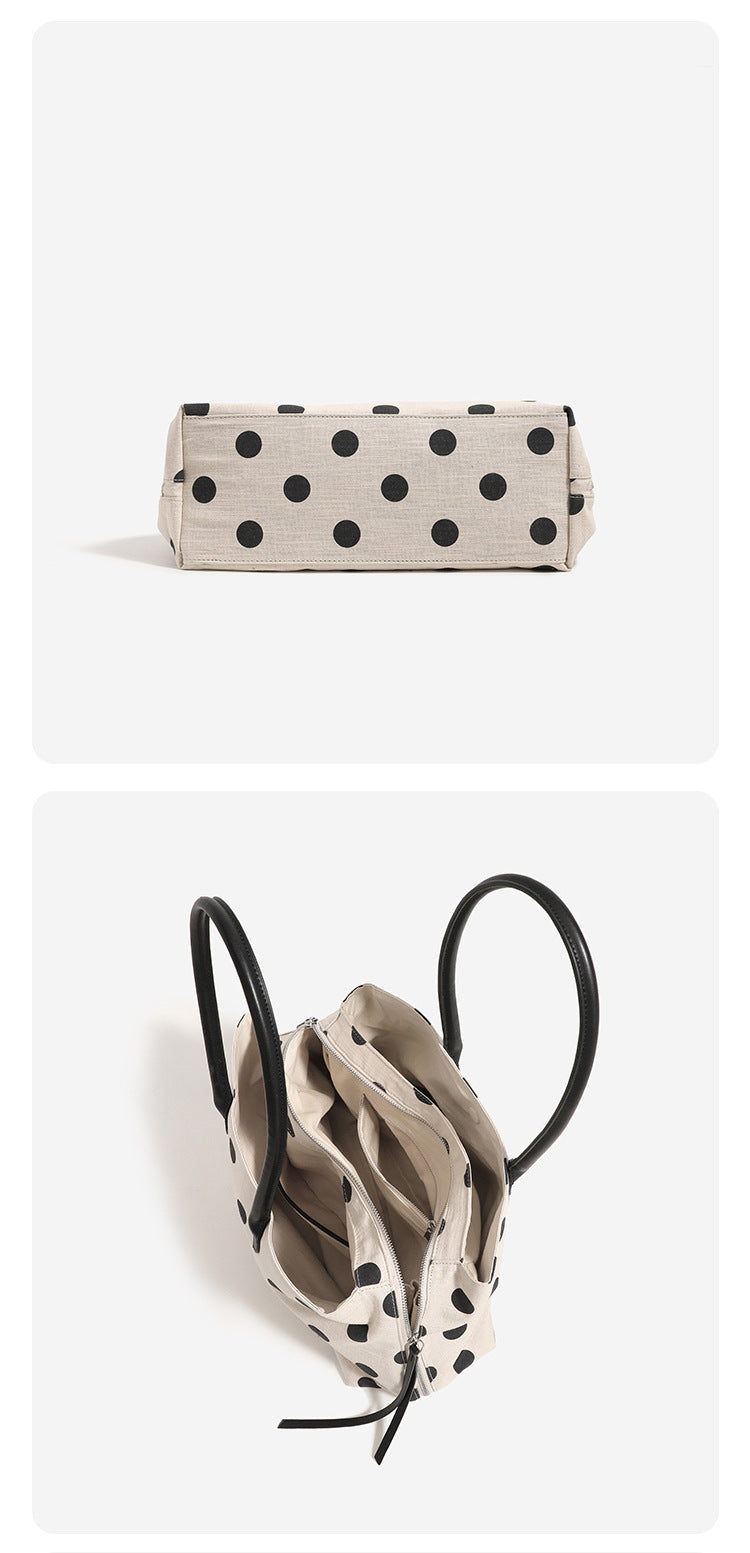 Cream canvas tote bag with black polka dots, rounded leather-look handles, and zip-top closure, detail view 11
