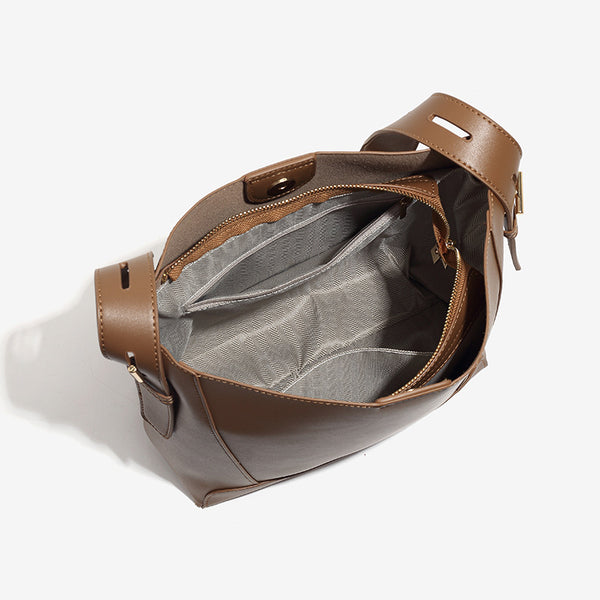 Structured smooth leather-look bucket shoulder bag with long adjustable strap and gold-tone buckle hardware in brown, detail