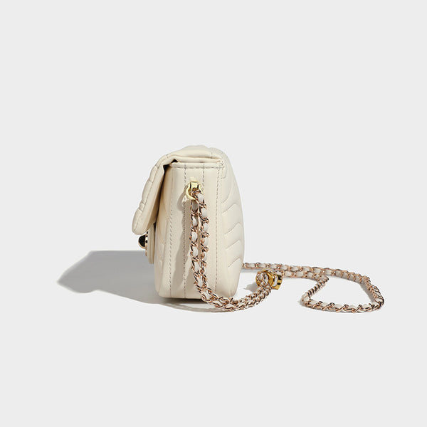 Compact cream quilted flap crossbody bag with wave stitching, gold-tone chain strap, and four-petal turn-lock clasp, detail