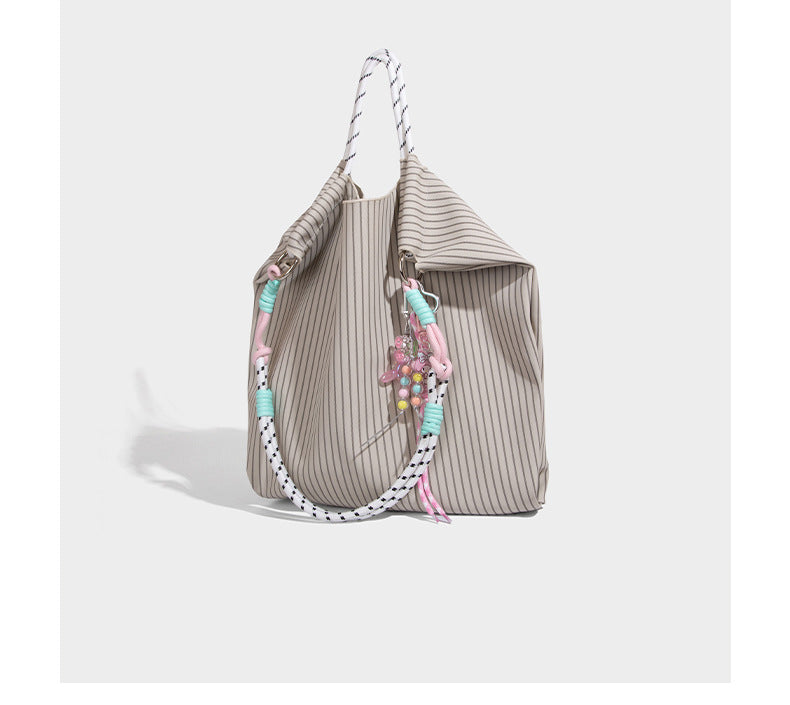 Slouchy pinstripe tote bag with braided rope handles, metal ring hardware, and colorful knotted rope charm, detail view 13
