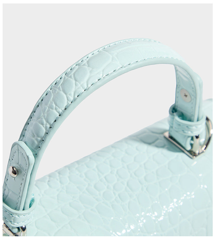 Small structured rectangular satchel with glossy crocodile-embossed finish, arched top handle, front flap, and silver-tone