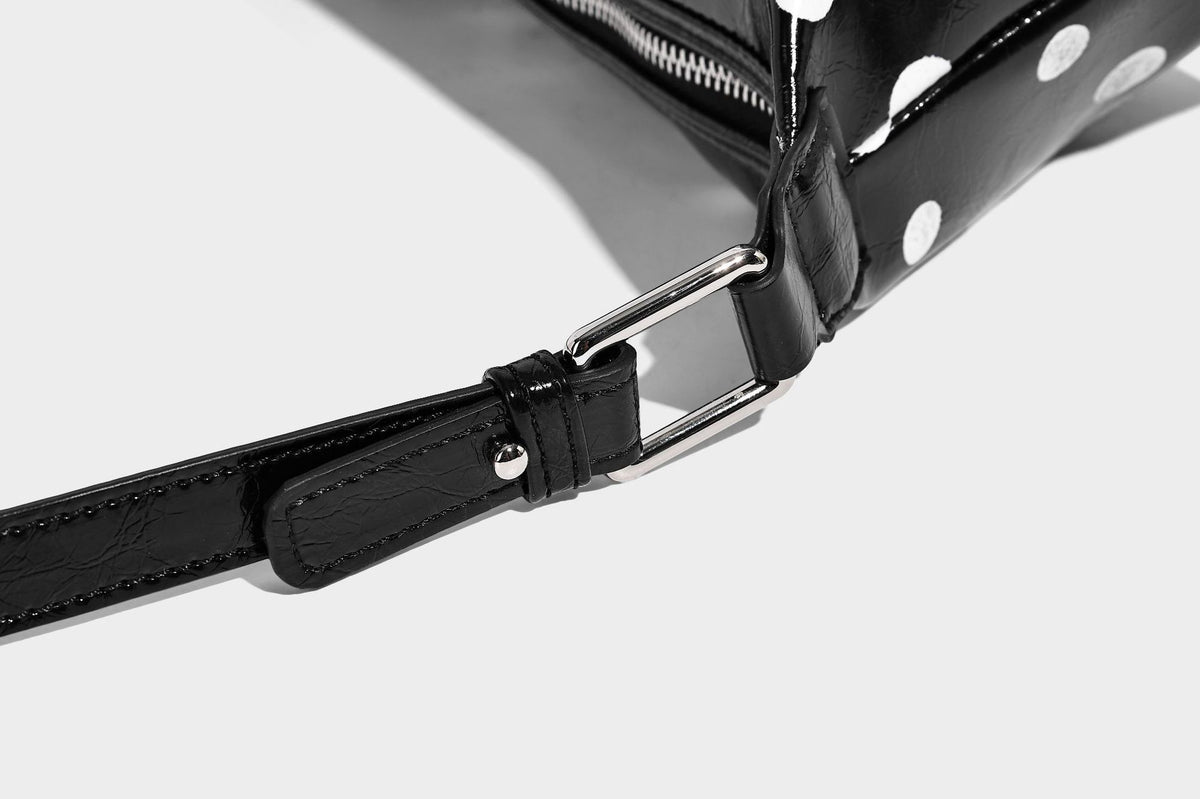 Kompakte glänzende Hobo-Schultertasche in Schwarz mit weißen Punkten, Reißverschluss, Beschlägen in Gunmetal und befestigtem Überschlag vorne