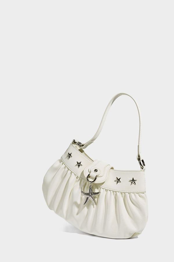 Ruched shoulder bag with curved flap, silver star studs, dangling starfish charm, and adjustable crossbody strap, detail view