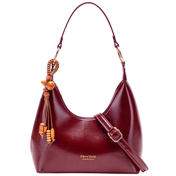 Glossy crescent hobo shoulder bag in deep burgundy with beaded wood tassel charm and gold-tone ring hardware, detail view 5