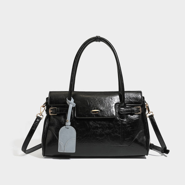 Structured glossy leather-look satchel bag with flap closure, gold-tone buckle accents, double top handles, detachable