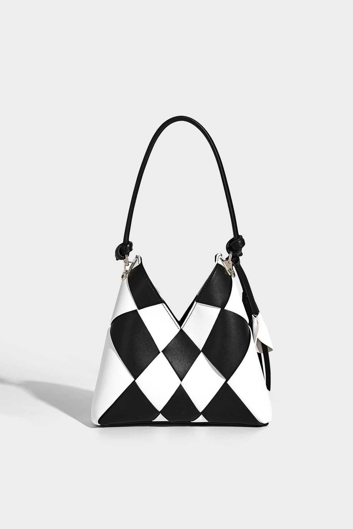 Compact bucket shoulder bag with black-and-white diamond patchwork panels, knotted top handle, gold-tone hardware, and