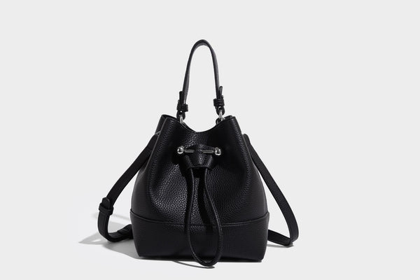 Small two-tone pebbled drawstring bucket bag with tan contrast base, metal toggle hardware, short top handle, and detachable