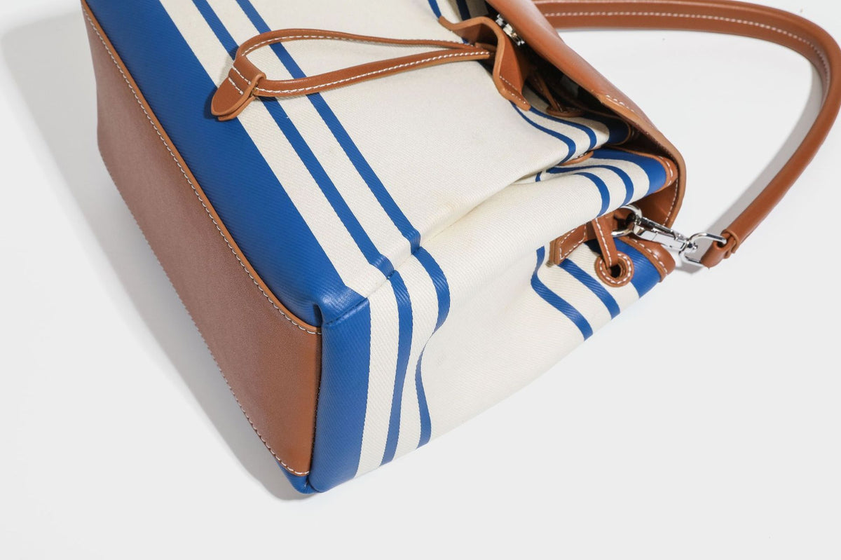 Cream canvas bucket bag with blue horizontal stripes, tan leather-look flap and trim, drawstring closure, silver-tone, detail