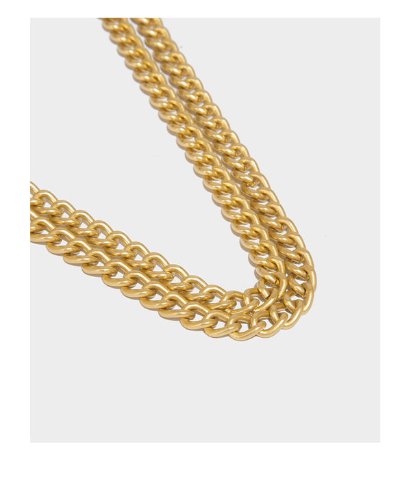 Structured rectangular crossbody bag with glossy finish, three vertical gold-tone embossed plaques, and gold chain strap
