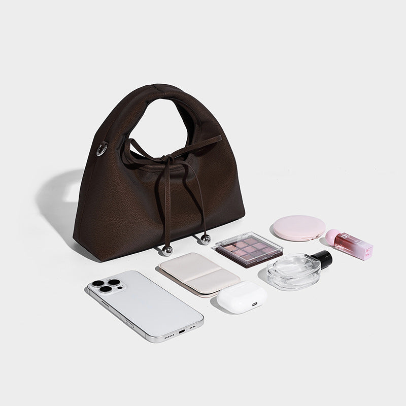Pebbled matte trapezoid top-handle bag with drawstring bow closure, bead-tipped cords, silver-tone hardware, and detachable