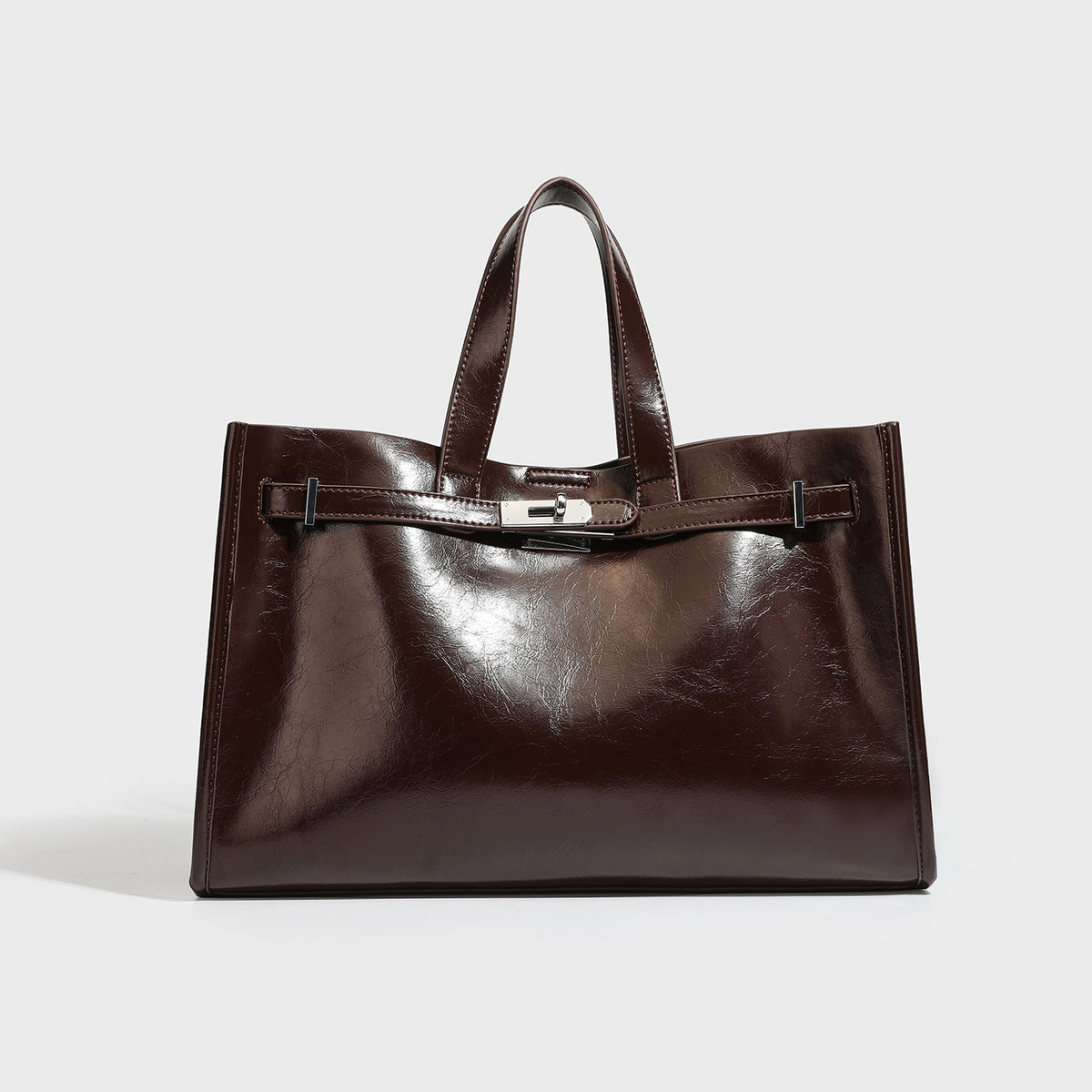 Structured glossy black leather-look tote bag with front turn-lock clasp, dual top handles, and detachable shoulder strap