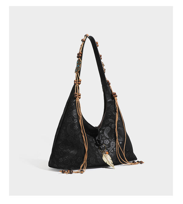 Slouchy boho hobo shoulder bag in embossed brown suede-look finish with beaded strap, cord tassels, and brass-tone leaf