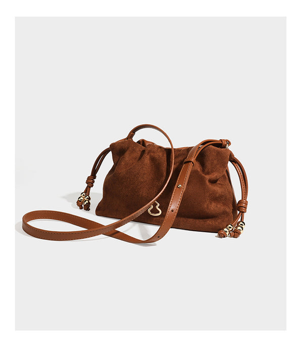 Suede-look drawstring shoulder bag in brown with smooth trim, knotted bead drawstring closure, slim adjustable strap, and