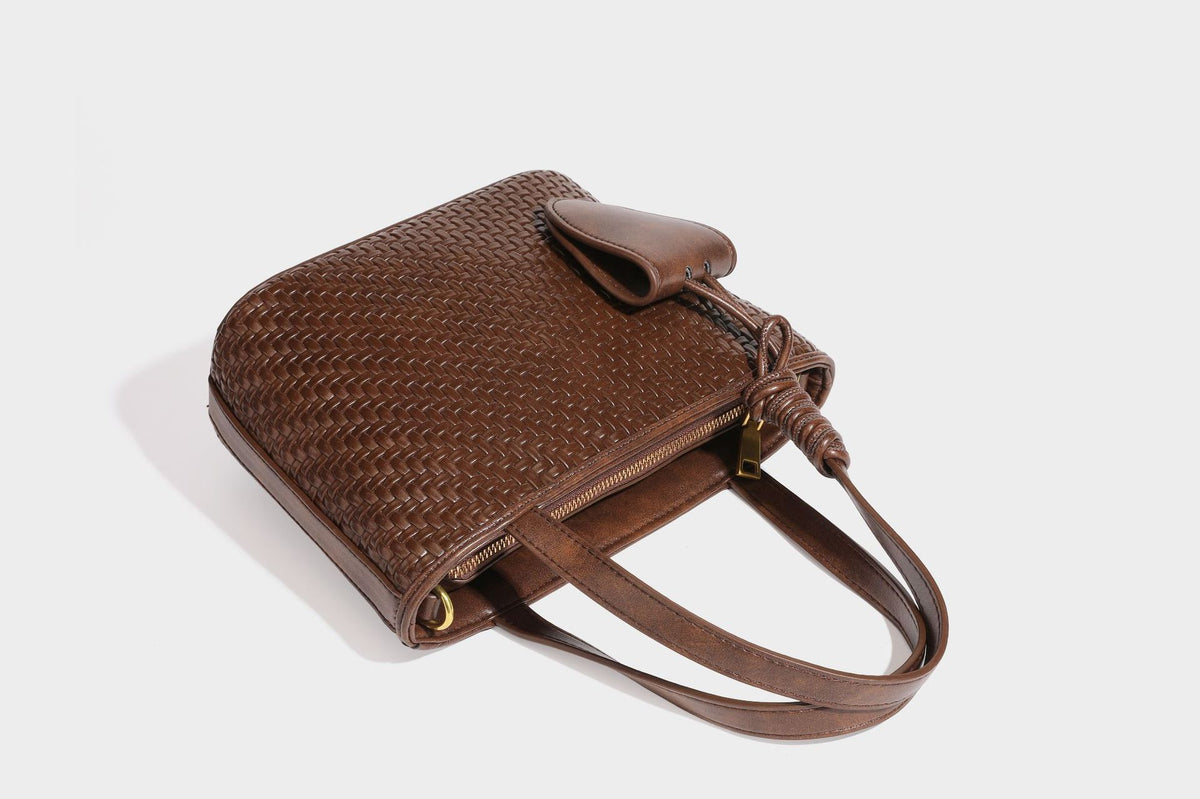 Strukturierte Tote Bag mit gewebter Oberfläche in Braun, goldfarbenen Metalldetails, seilumwickelten Tragegriffen, einer kleinen Fronttasche und weiteren Details