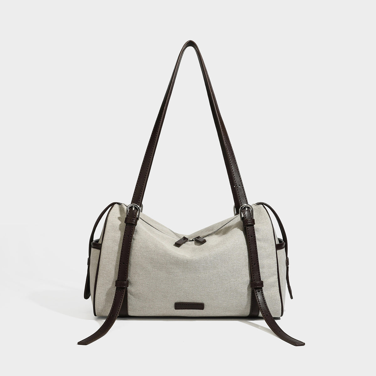 Cream canvas barrel shoulder bag with dark brown leather-look straps, trim, and silver-tone hardware, front view