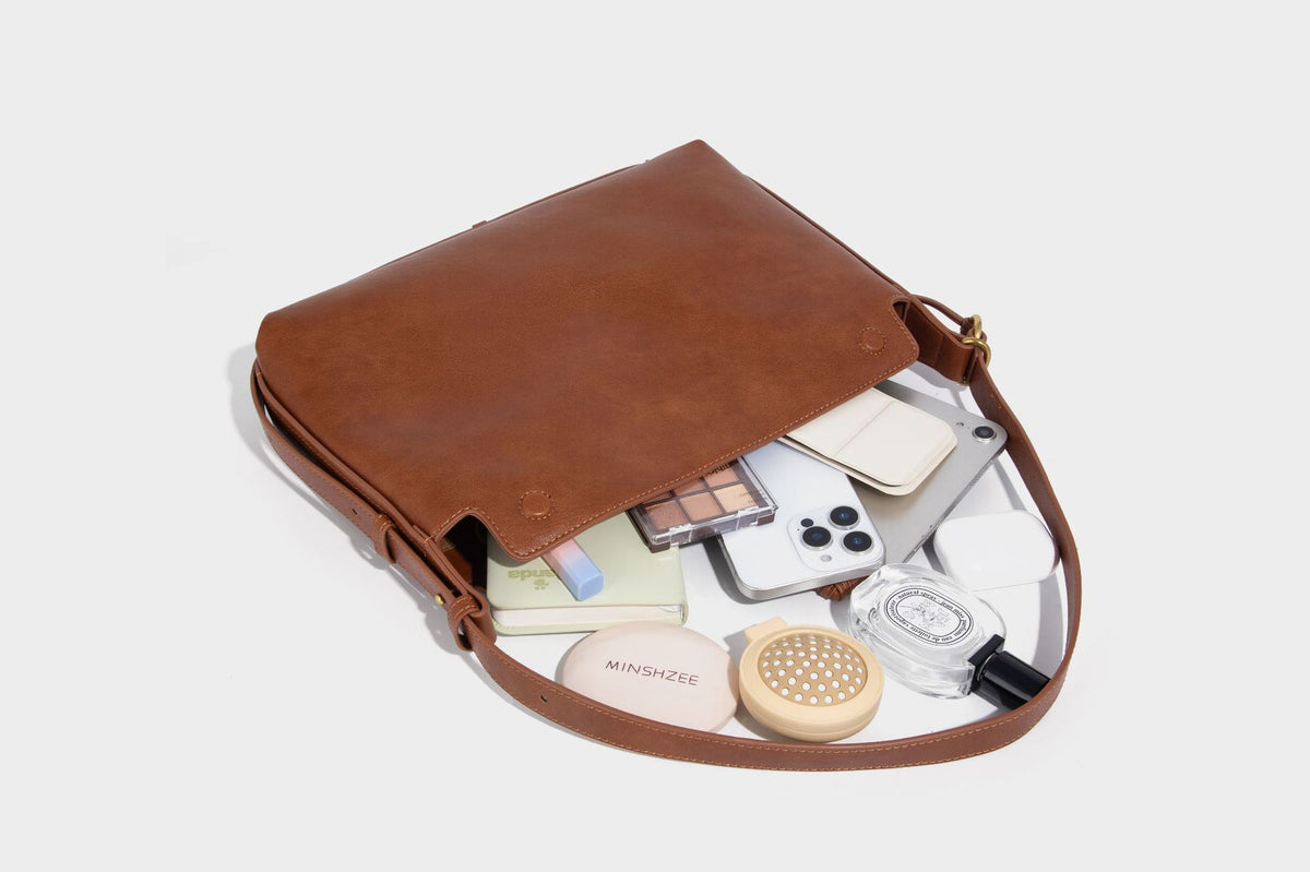 Slouchy brown leather-look shoulder bag with knotted drawcord tie closure, gold-tone ring hardware, and long adjustable