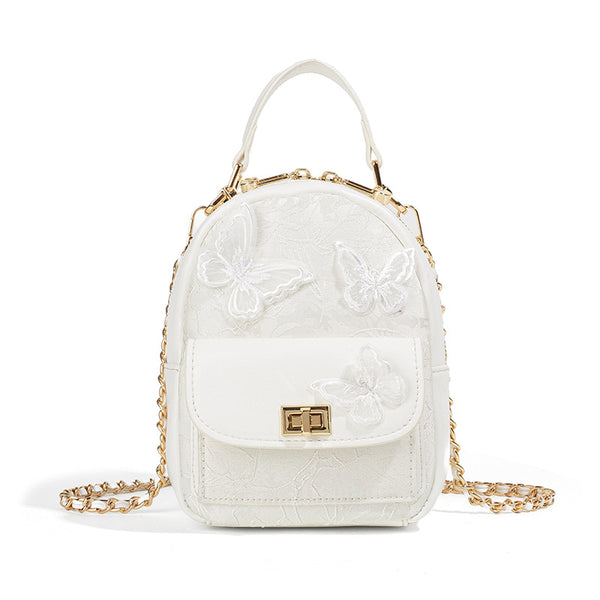 Structured mini backpack handbag with butterfly embroidery, gold-tone chain strap, and turn-lock front flap pocket, detail