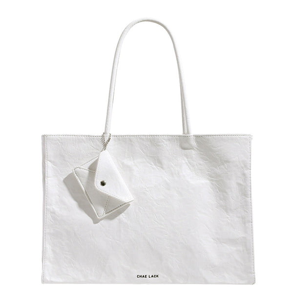 Structured rectangular crinkle leather-look tote bag with long rounded handles, zip top, and envelope-style hanging tag