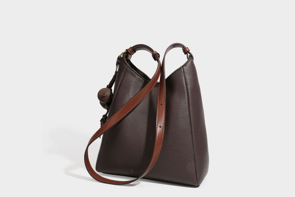 Hobo-Schultertasche in dunklem Espresso mit genarbter Oberfläche, warmen cognacfarbenen Details, verstellbarem schmalem Riemen, goldfarbenen Ringbeschlägen und geknotetem