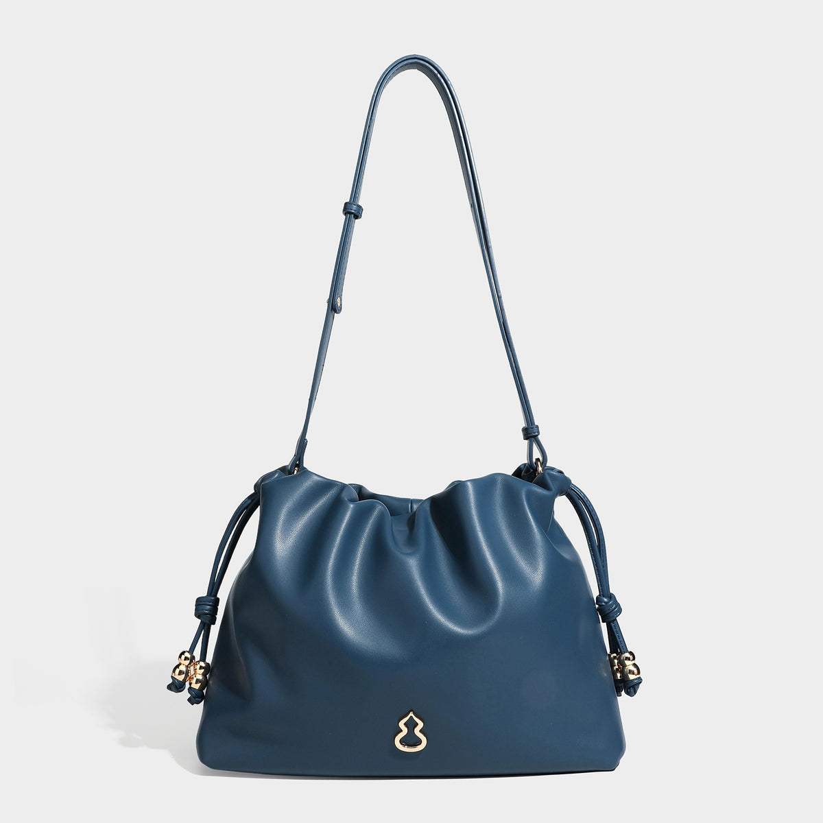 Slouchy ruched drawstring shoulder bag in smooth leather-look finish with gold-tone emblem and slim adjustable strap, detail