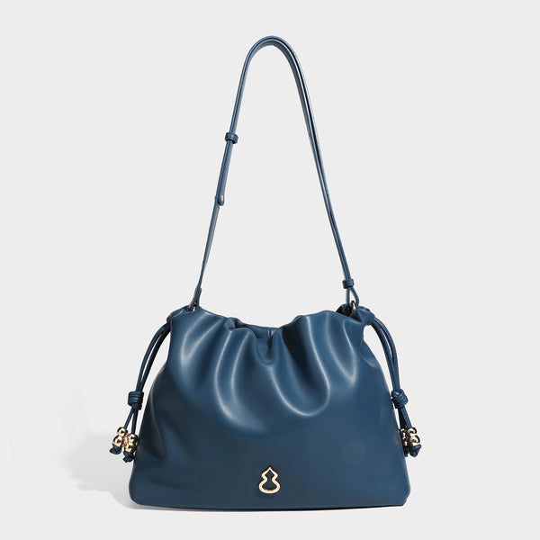 Slouchy ruched drawstring shoulder bag in smooth leather-look finish with gold-tone emblem and slim adjustable strap, detail