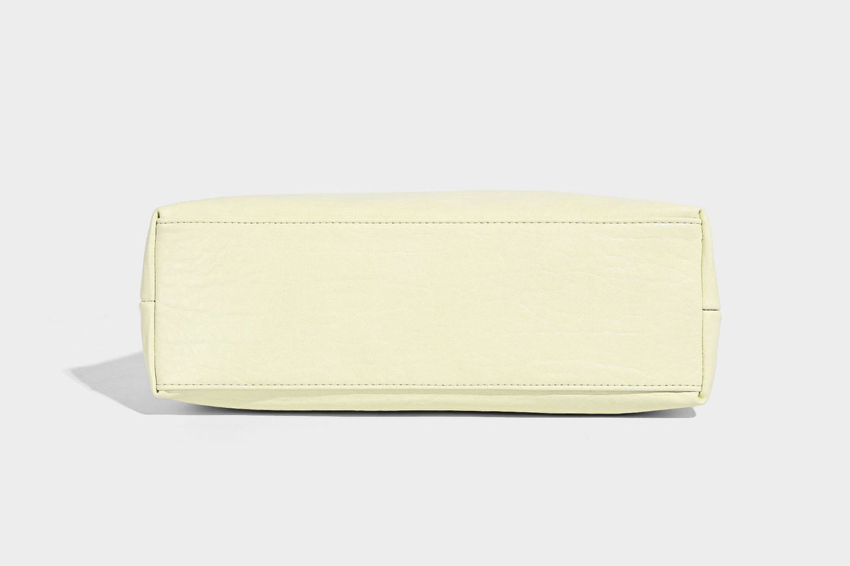 Slouchy hobo shoulder bag in pale yellow glossy pebbled leather-look finish with single shoulder strap and detachable front