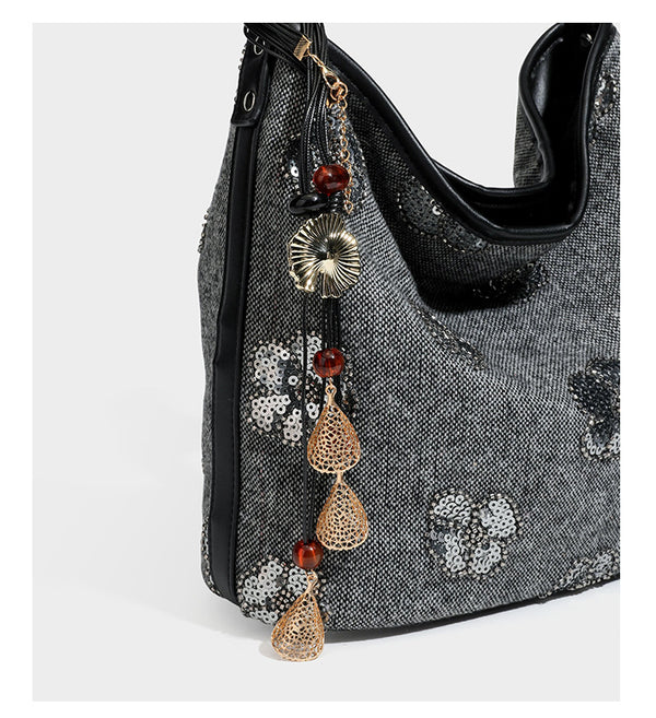 Lässig fallende Hobo-Schultertasche aus anthrazitfarbenem Webstoff mit floraler Stickerei aus silberfarbenen Pailletten, schwarzem Besatz in Lederoptik und langem