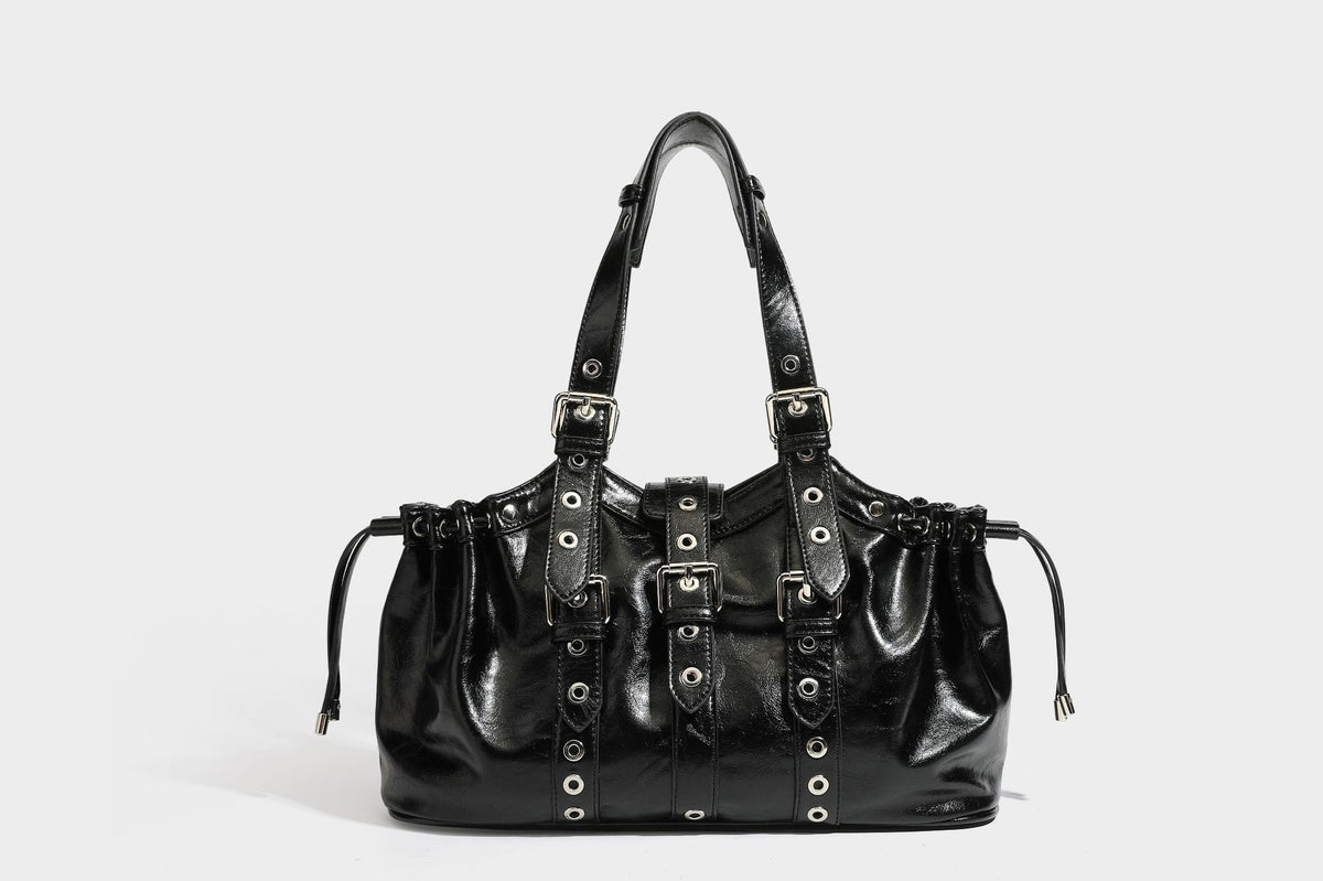 Large black glossy leather-look tote bag with silver buckle straps, eyelet grommet panels, drawstring side gathers, and