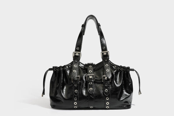 Large black glossy leather-look tote bag with silver buckle straps, eyelet grommet panels, drawstring side gathers, and
