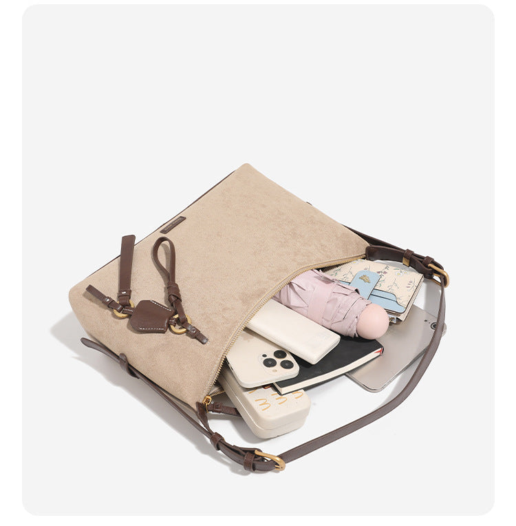 Hobo-Schultertasche in sandfarbener Velourslederoptik mit dunkelbraunen Riemen in Lederoptik, goldfarbenen Metalldetails, Reißverschluss oben und hängendem