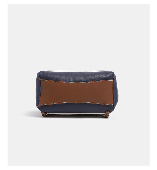 Cremefarbene Canvas-Beuteltasche mit horizontalen marineblauen Streifen, cognacfarbenem Besatz und Überschlag in Lederoptik, goldfarbenen Metalldetails und wandelbarem