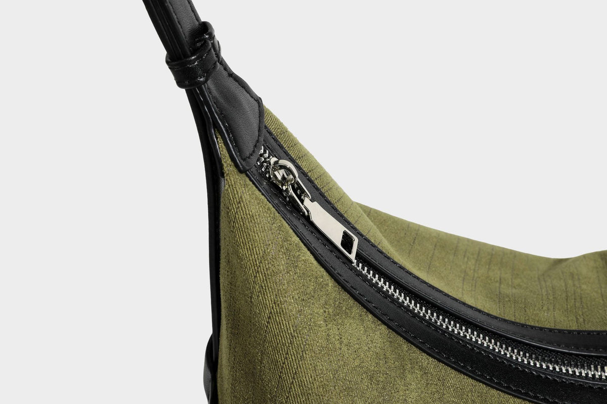 Slouchy olive green canvas hobo shoulder bag with black leather-look trim, zip-top closure, and adjustable strap, detail view