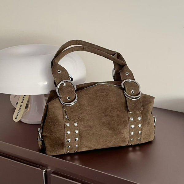 Matte suede-finish barrel bag with silver stud panels, oversized ring hardware, and dual top handles, front view