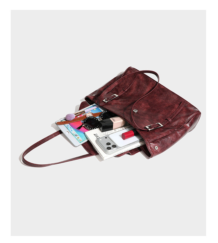 Large structured shoulder tote bag in wine red textured leather-look finish with front flap closure and silver-tone buckle