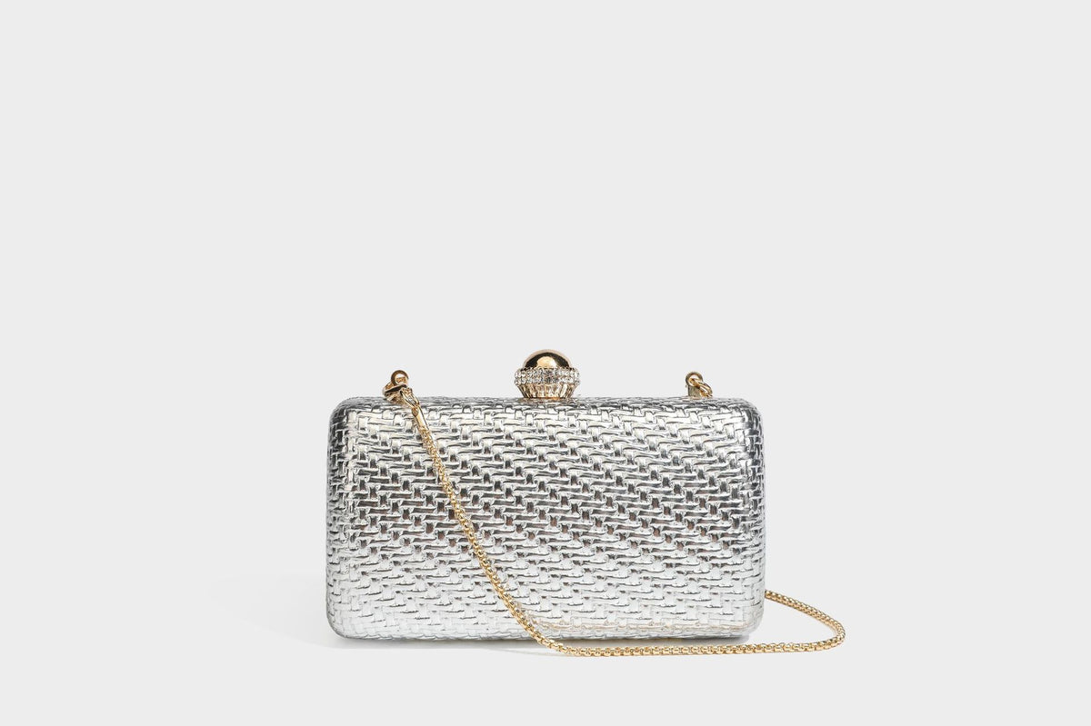 Small structured metallic woven-texture box clutch bag with jeweled kiss-lock dome clasp and slim gold chain strap, detail