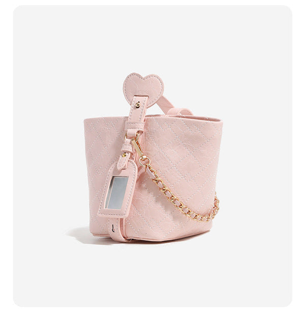 Small diamond-quilted bucket bag with gold-tone chain accent, heart strap detail, hanging tag, and matching zip coin pouch
