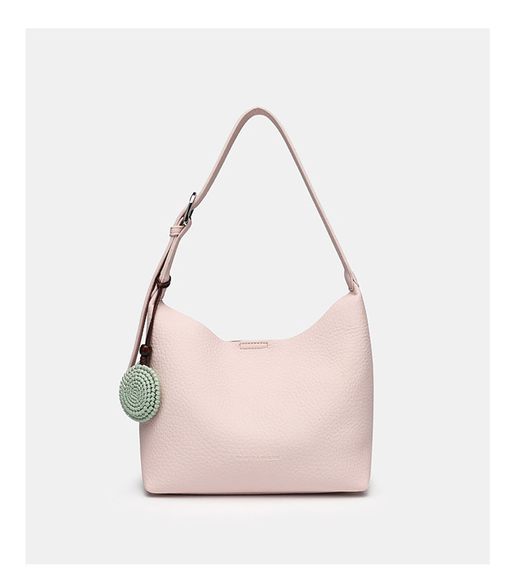 Slouchy hobo shoulder bag in pale yellow pebbled texture with woven charm, adjustable strap, matching zip pouch, and, detail