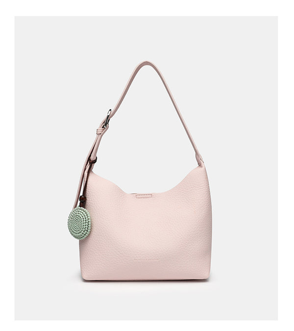 Slouchy hobo shoulder bag in pale yellow pebbled texture with woven charm, adjustable strap, matching zip pouch, and, detail