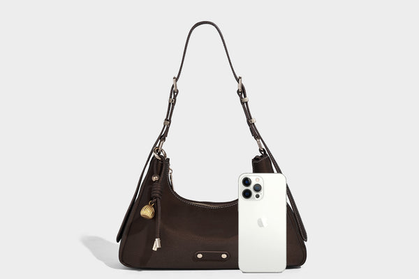 Crescent hobo shoulder bag in pebbled leather-look finish with top zipper, adjustable strap, gold-tone ring hardware, and