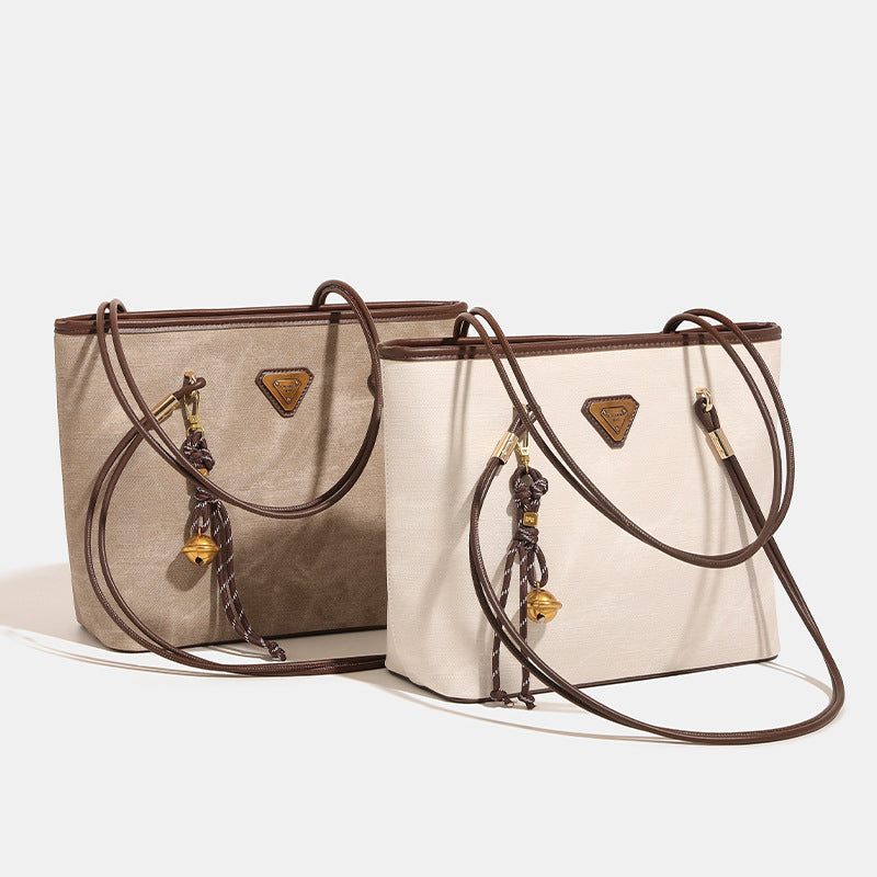 Großer strukturierter Shopper mit offenem Oberteil in Creme mit dunkelbraunen Besätzen in Lederoptik, zwei Schulterriemen und dreieckigem Logo-Badge