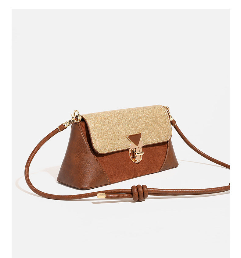 Structured trapezoid shoulder bag with pale textured flap, gold-tone triangular turn-lock closure, and long knotted cord