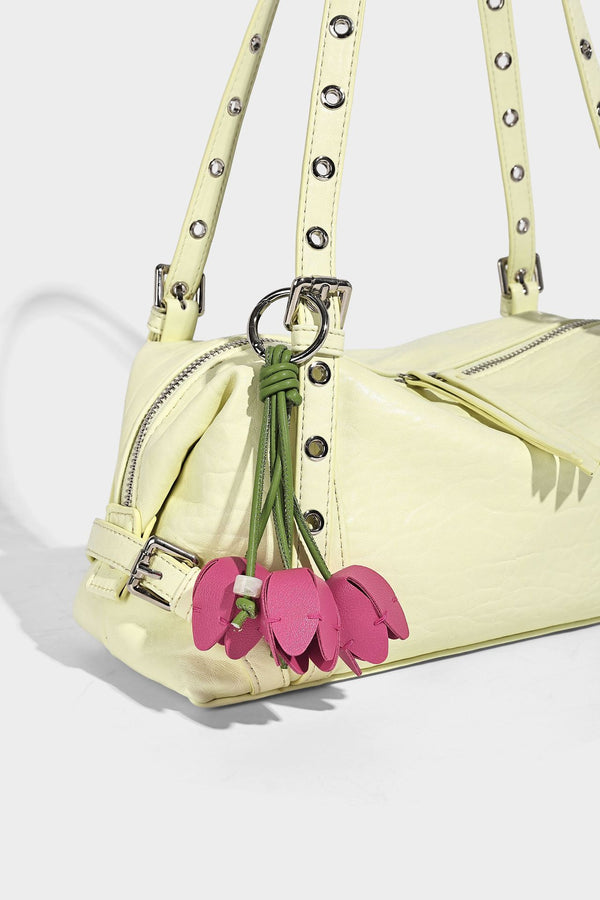 Pale yellow leather-look barrel bag with silver grommet-studded shoulder straps, top zip closure, and pink tulip floral