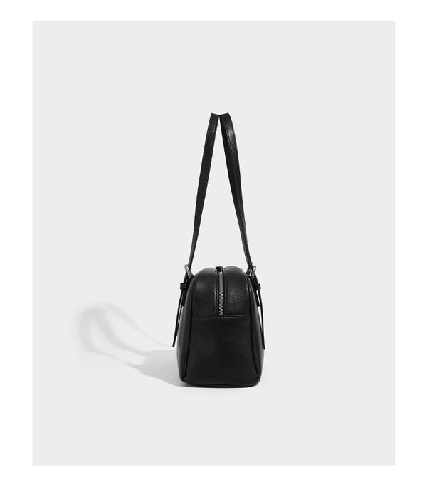 Structured dome-shaped shoulder bag with leather-look finish, top zipper closure, dual adjustable slim straps, and, detail