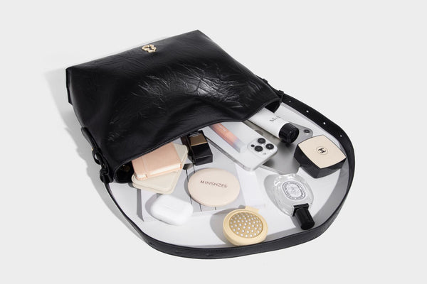 Large slouchy hobo shoulder bag in glossy crinkle leather-look finish with gold-tone emblem hardware and adjustable strap