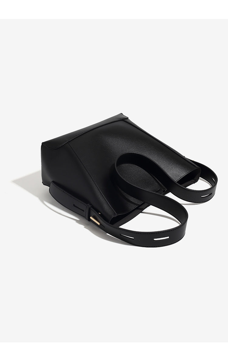 Structured smooth leather-look bucket shoulder bag with long adjustable strap and gold-tone buckle hardware in brown, detail